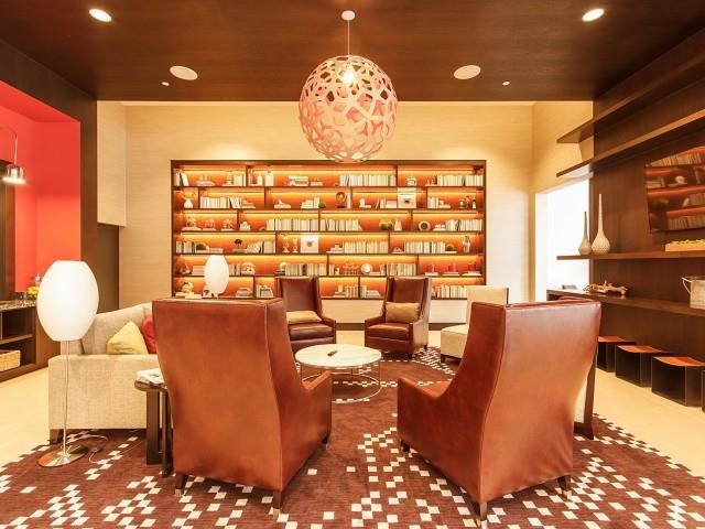 a living room with leather chairs and a library