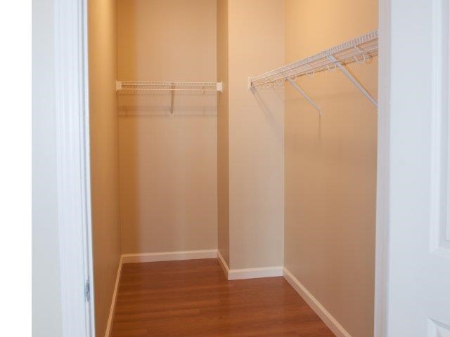 a walk in closet with a wood floor and white