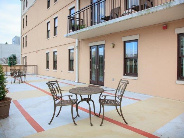 a patio with a table and chairs in front of a building