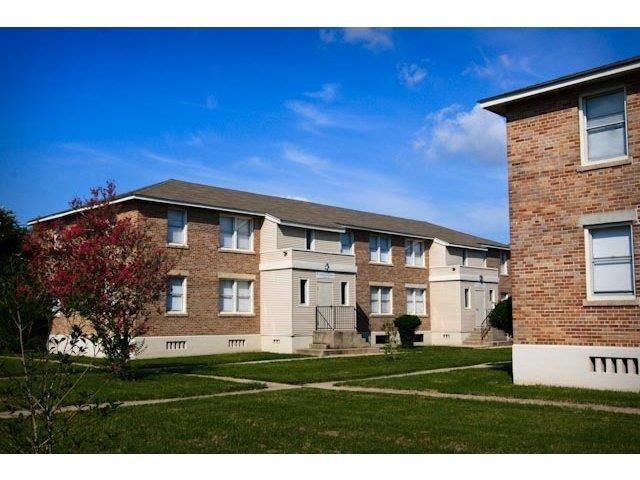 a brick apartment building with grass and a blue sky