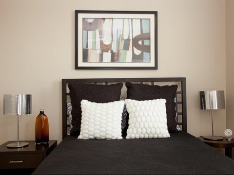 a bedroom with a black bed and a picture on the wall