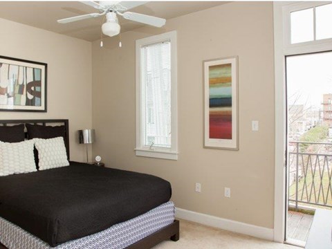 a bedroom with a black bed and a ceiling fan