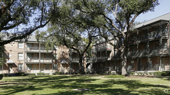 A tree in front of a building with a balcony.