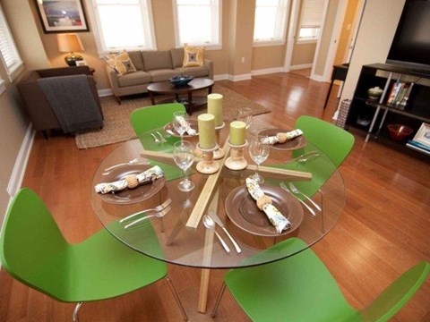 a glass table with green chairs in a living room