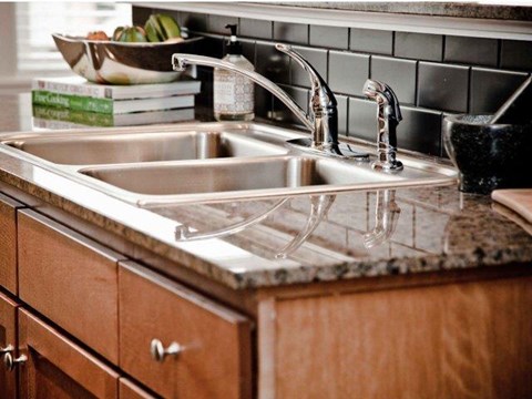 a kitchen sink with two faucets on a counter top