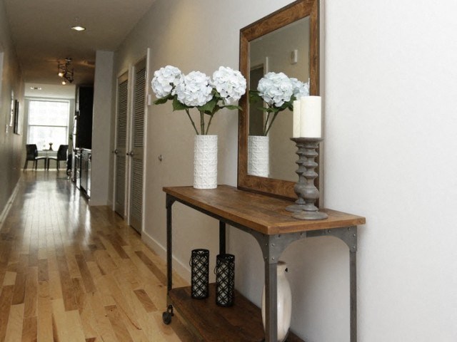 a hallway with a table with flowers and a mirror