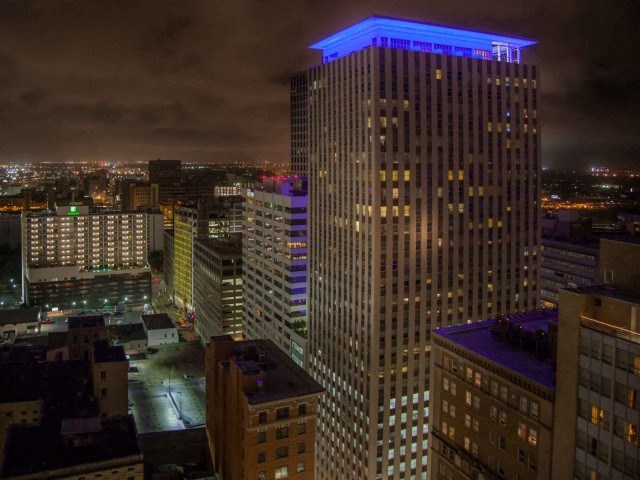 a city skyline at night with a tall building lit up in blue