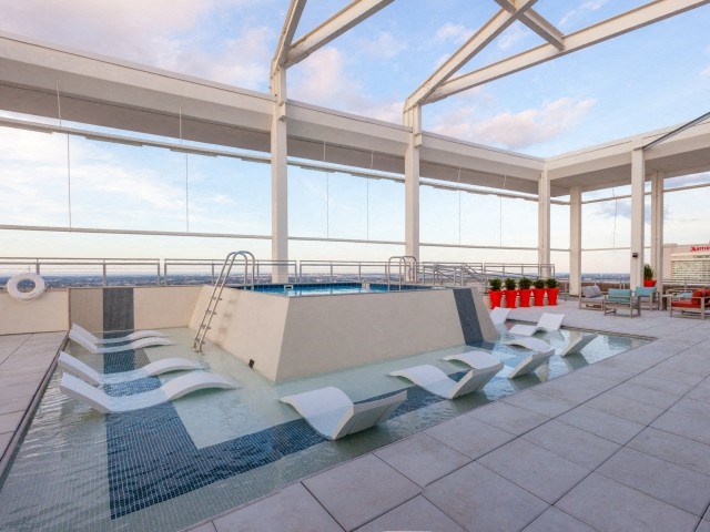 a pool on the roof of a building with lounge chairs