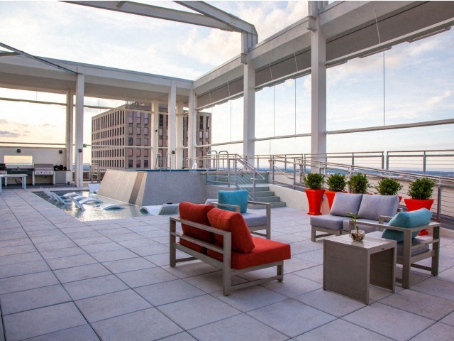 a rooftop patio with chairs and a pool