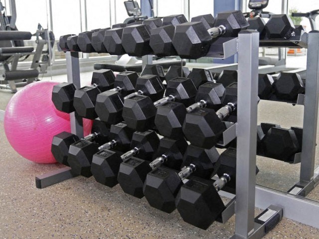 a pile of dumbbells in a gym with a pink ball