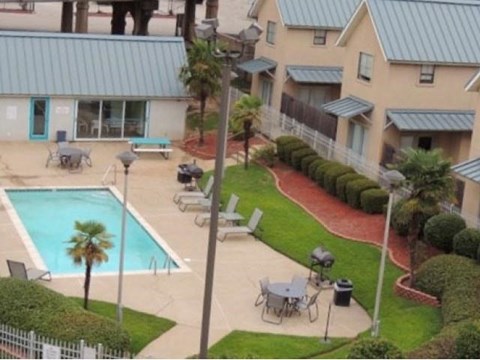 A pool surrounded by chairs and a fence.