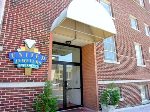 The entrance to United Jewelers with a brick wall and a white awning.