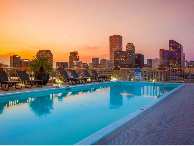 a pool with a city skyline in the background at sunset