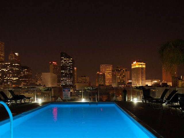 a pool on a rooftop with a city skyline at night