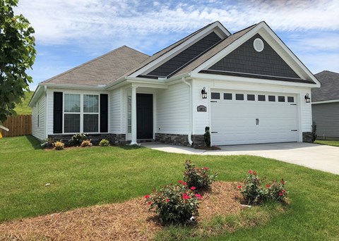 A white house with a grey roof and a garage door.