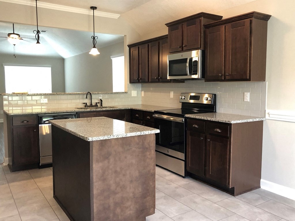 A kitchen with brown cabinets and a granite counter.
