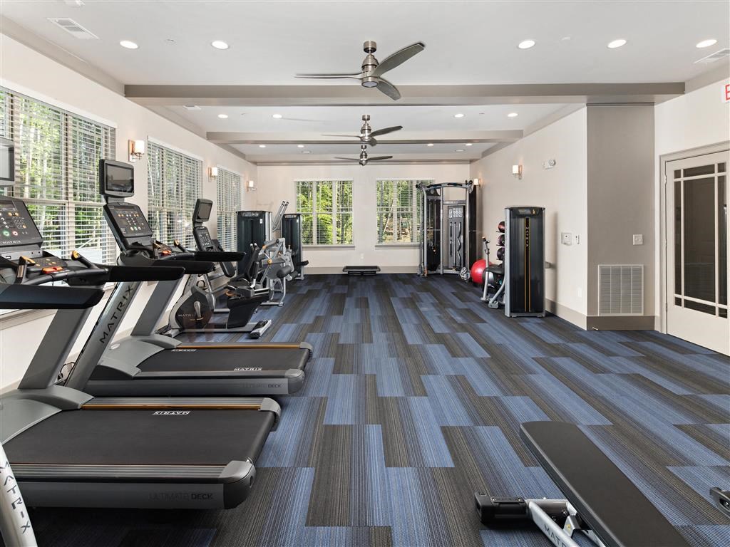 a gym with cardio machines and a ceiling fan