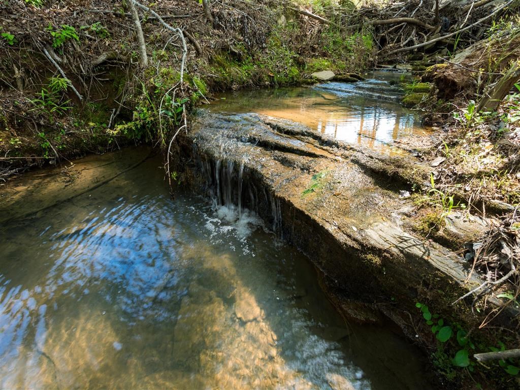 a stream with a waterfall flowing over a rock