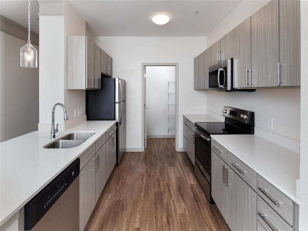 an empty kitchen with wooden floors and white cabinets