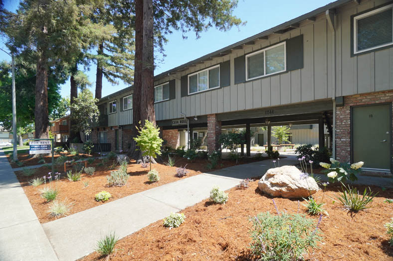 the front of a building with a sidewalk and landscaping