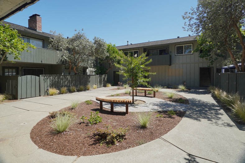 a courtyard with a bench and a tree in front of a house