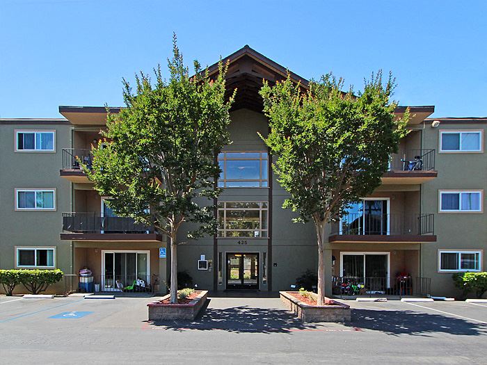 an apartment building with two trees in front of it