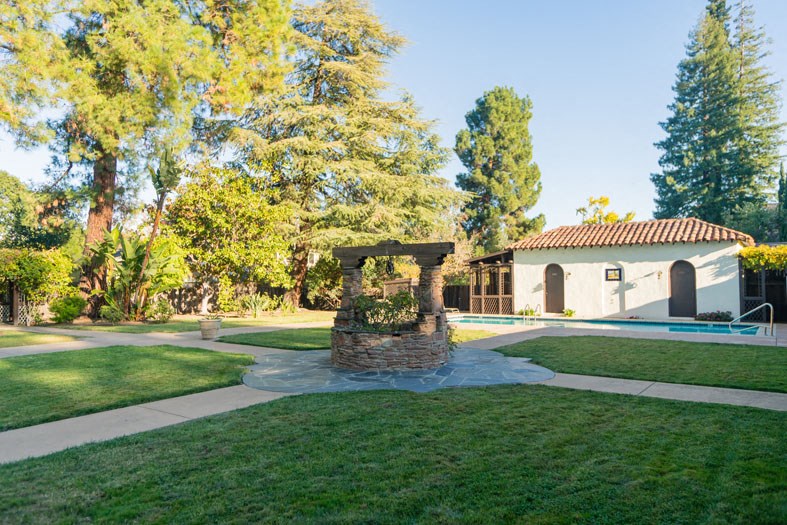 a stone gazebo in a yard with a pool and trees