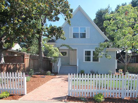 a white picket fence in front of a blue house