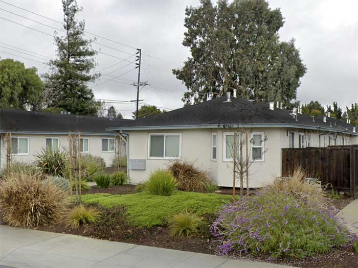 A row of houses with a green lawn in front.
