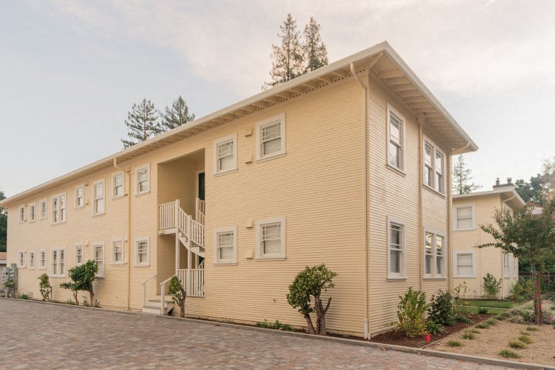 a yellow apartment building with a street in front of it