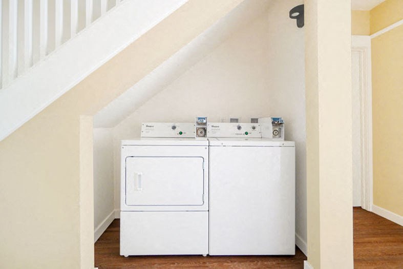 a washer and dryer in a room under a staircase