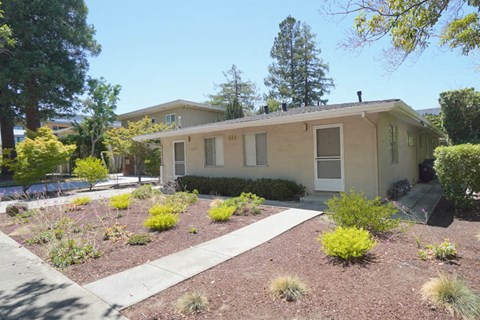 a small tan house with a garden in front of it
