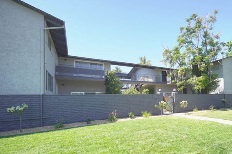 A modern house with a grey wall and a green lawn in front.