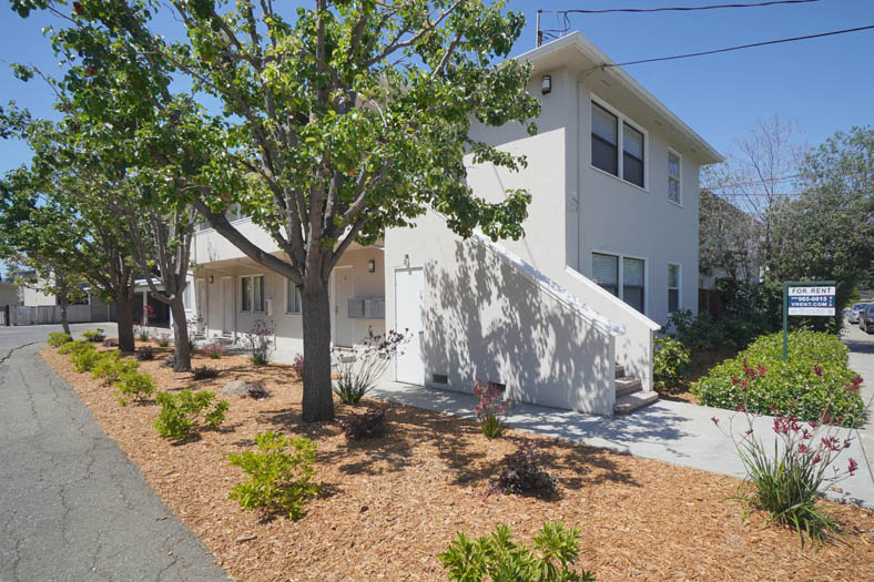 a white house with a sidewalk and trees in front of it
