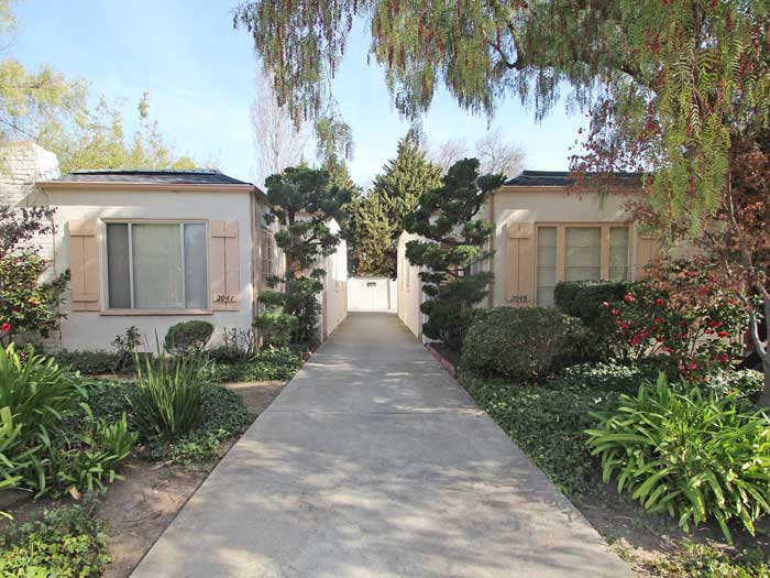 a house with a sidewalk and trees and plants