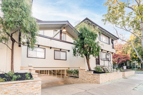 a house with a sidewalk and trees in front of it