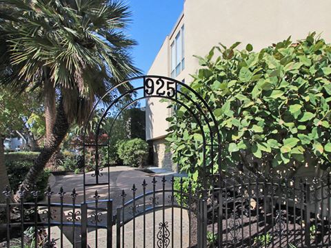 an apartment building with a gate and a palm tree