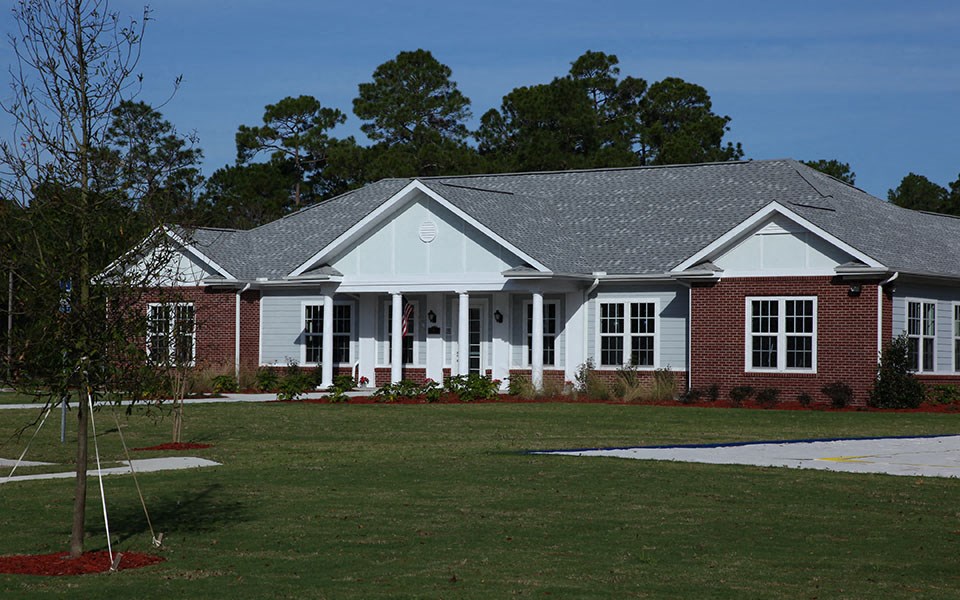 a large brick house with white pillars and a lawn