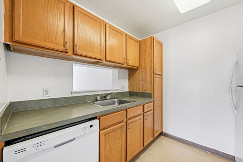 A kitchen with wooden cabinets and a white dishwasher.