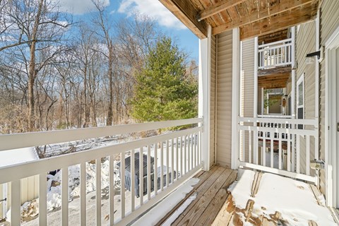 A wooden deck with a white railing and a view of a snowy landscape.