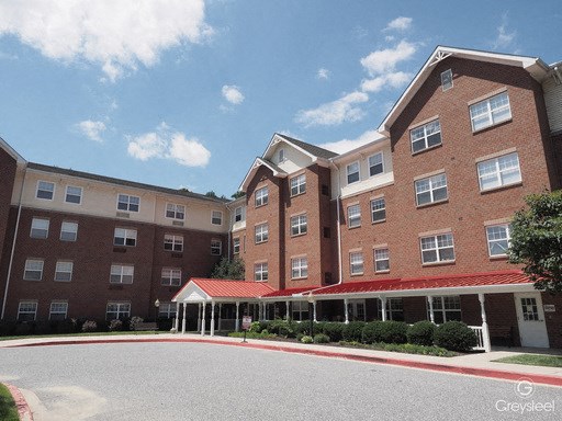 a large brick building with a red roof and a street in front