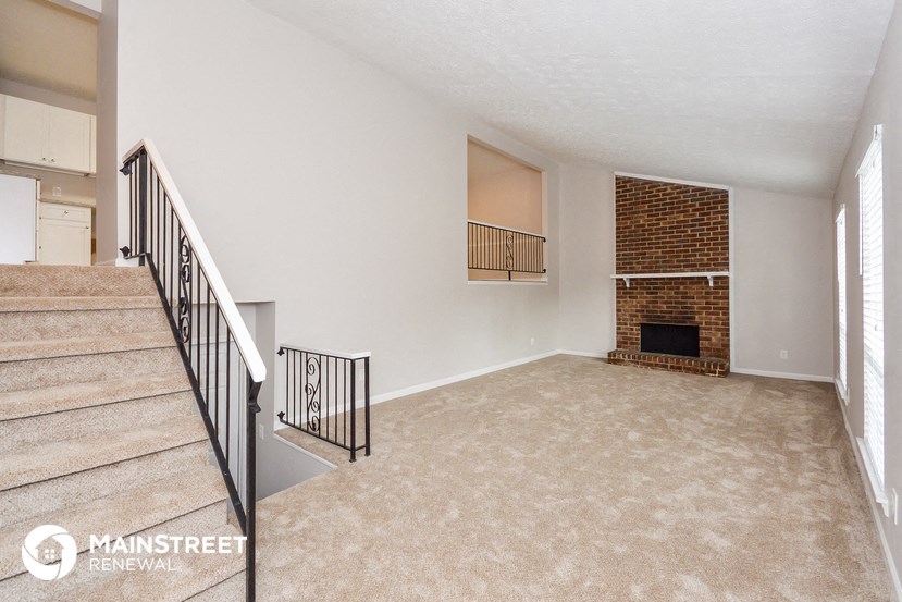 an empty living room with a fireplace and stairs