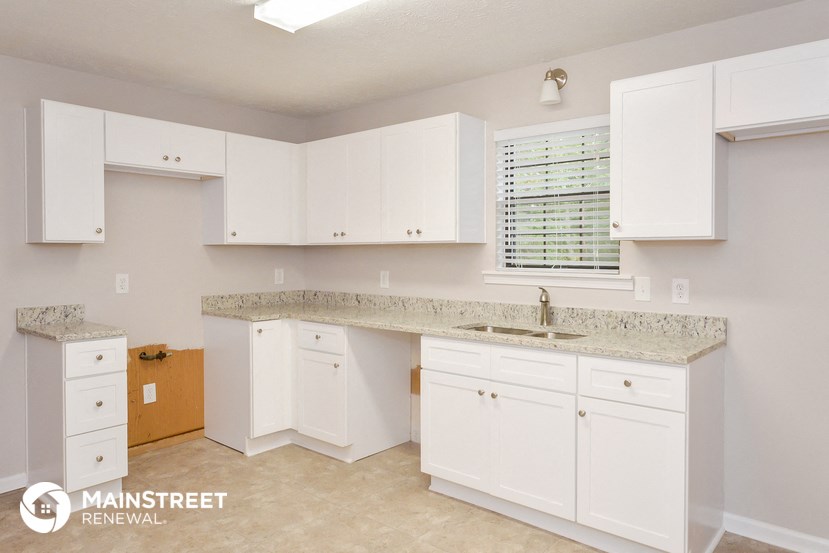 a kitchen with white cabinets and granite counter tops and a sink