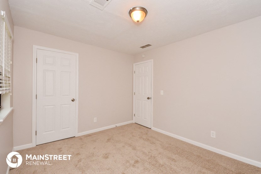 the upstairs bedroom has a carpeted floor and two closet doors