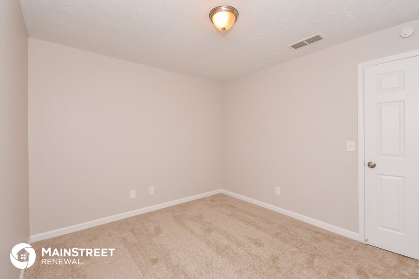 the upstairs bedroom of this house has a carpeted floor and a white door
