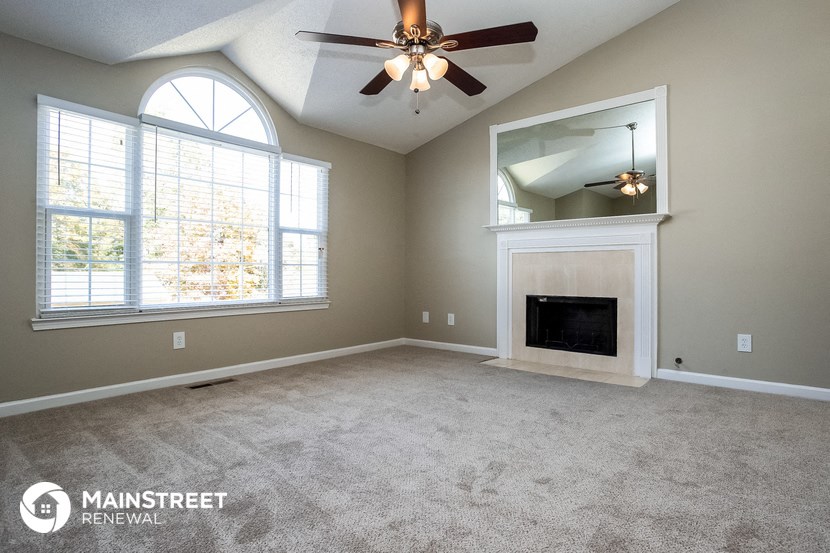 an empty living room with a fireplace and a ceiling fan