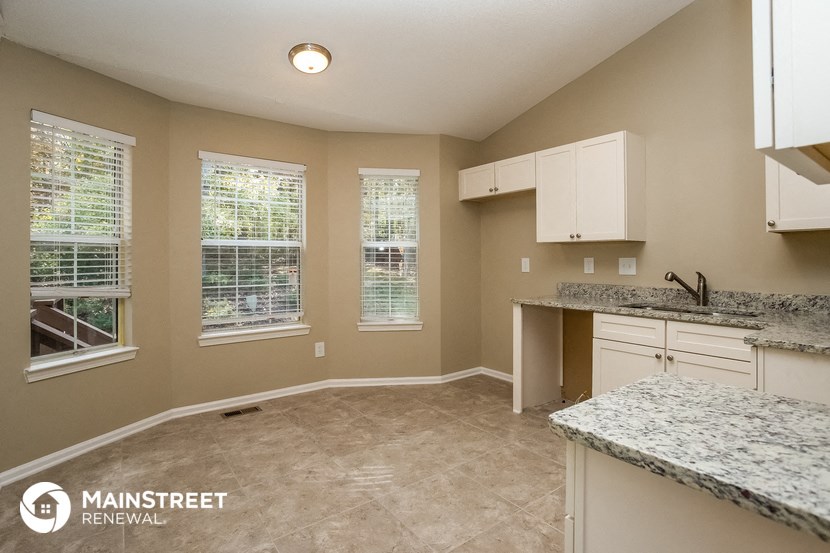 an empty kitchen with granite counter tops and white cabinets