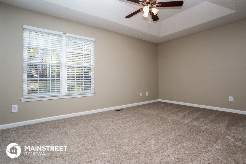 an empty living room with a ceiling fan and a window
