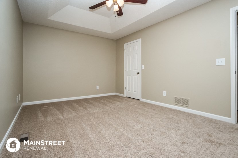 an empty living room with a ceiling fan and a door