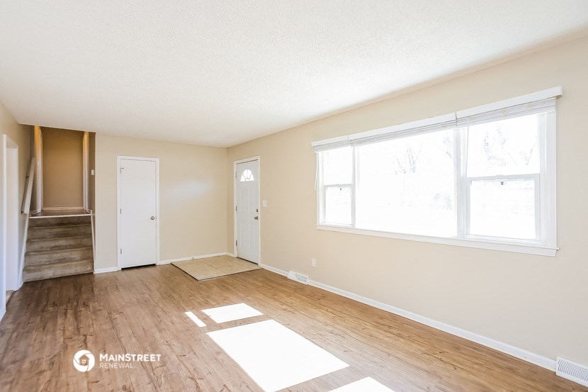 a living room with a hard wood floor and a large window